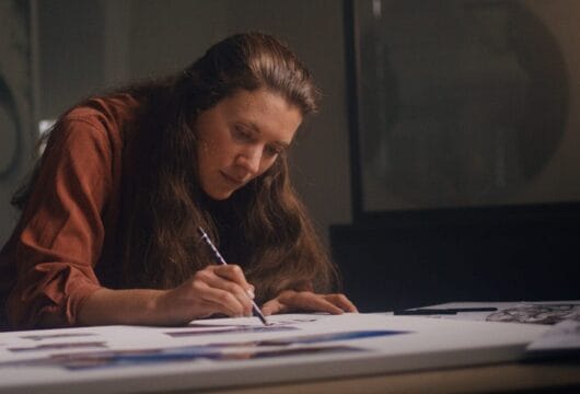 malende Frau steht über Tisch gebeugt